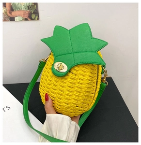 Close-up of pineapple-shaped woven straw crossbody bag with green leaf leather flap