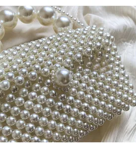 Gros plan d'un sac à main en perles crème avec une grande boucle et bandoulière tissée