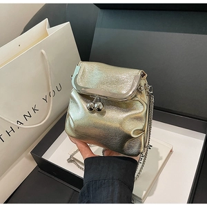Macro view of golden pleated leather mini bag with silver ball clasp and metal chain