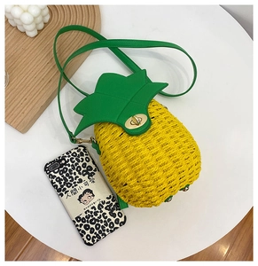 Detail of pineapple-shaped straw crossbody bag with green leaf flap and gold twist lock