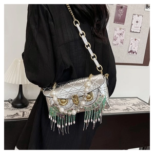 Close-up of owl-shaped silver crossbody bag with diamond quilting and fringe details