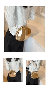 Detail of a heart-shaped gold mirror acrylic bag with a metallic chain strap