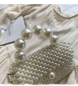 Détail du sac à main en perles tissées crème avec grande poignée sur tissu plissé