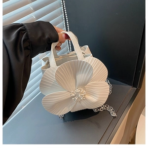 Detailed shot of white floral petal handbag featuring textured ruffles and silver chain
