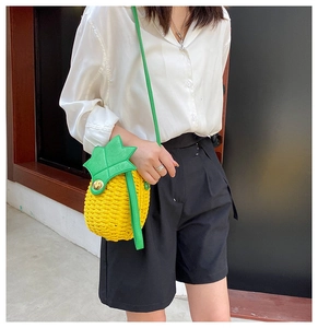 Close-up of woven pineapple crossbody bag with green leaf detail and gold twist lock