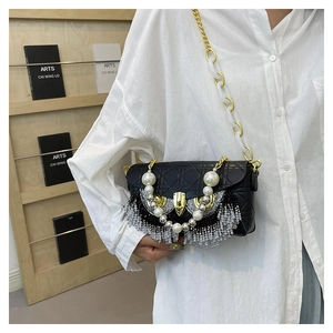 Detail of black quilted shoulder bag with crystal fringe and pearl decor on white shirt