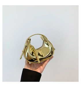 Macro view of a mini crescent handbag with shiny gold mirror finish and zipper detail