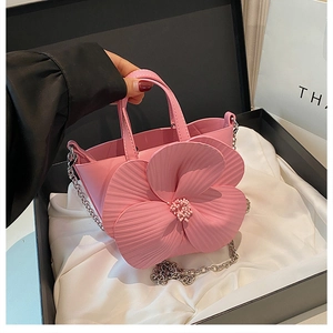 Detailed view of pink flower bucket bag with 3D petals and silver chain on white silk