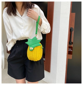 Close-up of woven pineapple bag featuring green leaf handle and golden metal twist lock