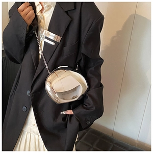 Polished silver pebble shaped acrylic mirror bag with metallic chain strap worn over blazer