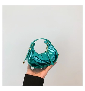 Detailed close-up of a mini metallic teal crescent handbag with gold zipper and rivet accents