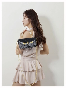Detail of owl-shaped black crossbody bag with rhinestone tassels and pearl handle
