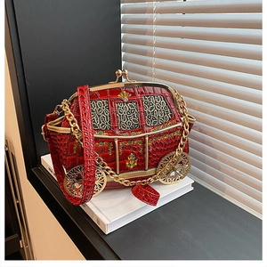 Detail of red pumpkin carriage handbag with embossed crocodile texture and gold chain