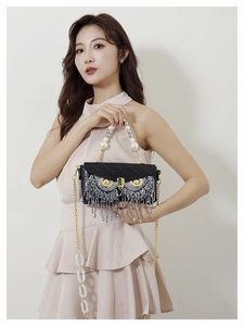 Detail of owl-shaped crossbody bag featuring pearl handle and sequin tassel accents
