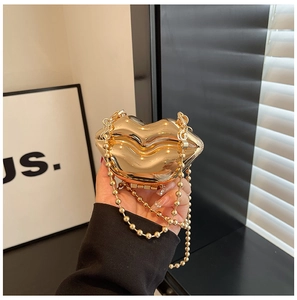 Detailed close-up of golden lip-shaped acrylic clutch bag with round beaded metal chain