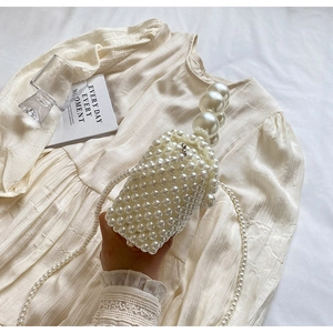 Détail d'un sac en perles avec poignées en perles géantes et bandoulière longue chaîne