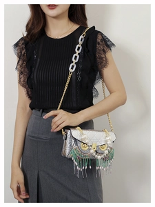 Detail of silver owl-shaped bag featuring colorful bead tassels and pearl embellishments
