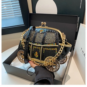 Detailed macro view of the luxury carriage bag featuring black crocodile texture and gold wheels