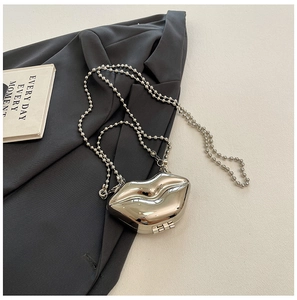 Detailed view of glossy silver lip-shaped acrylic clutch with detachable ball chain strap