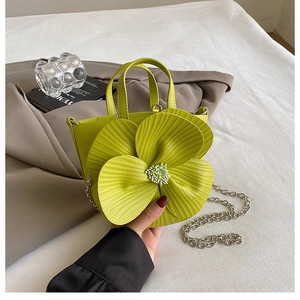 Detail of lime green bucket bag featuring a large 3D flower and silver chain strap