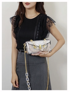 Detail of silver quilted bag featuring pearl fringe tassels and gold chain acrylic strap