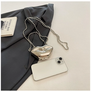 Macro shot of silver lip-shaped mini chain bag shown next to phone for size reference