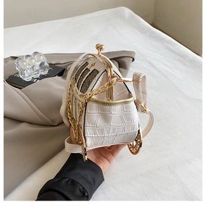 Detail of white crocodile texture carriage bag with floral embroidery and gold chain