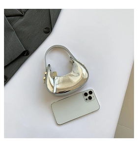 Mini silver mirror semi-moon handbag with gold hardware next to a smartphone for size