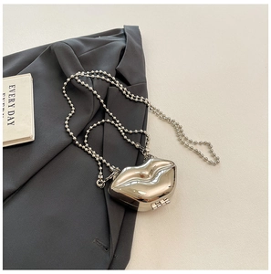 Close-up of a silver lip-shaped mini bag with metallic finish and bead chain strap