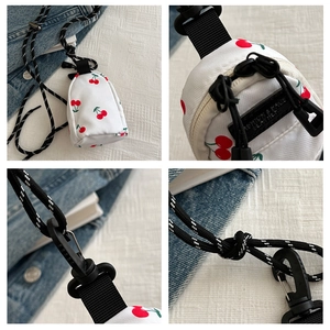 Detail of white canvas cherry print mini pouch with woven lanyard and metal zipper