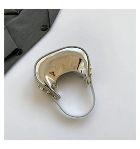 Top-down view of a shiny silver half-moon mini handbag with golden studs detail