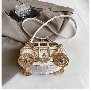 Detailed view of carriage-shaped white faux crocodile leather bag with floral embroidery
