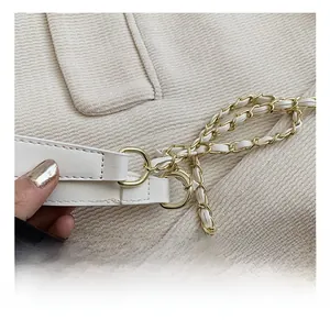 Détail de la boucle en D dorée et de la bandoulière en chaîne de cuir sur sac blanc