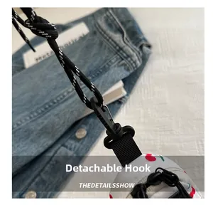 Detail of the black detachable hook and woven rope strap on the cherry print bag