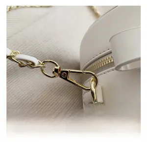 Détail du crochet en métal doré et de la bandoulière en chaîne de ce sac blanc