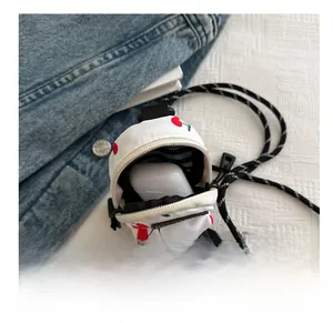 Detailed view of mini cherry print canvas bag holding a wireless earphone case