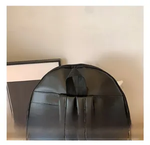 Close-up of black backpack handle and shoulder straps with fine stitching and matte zipper