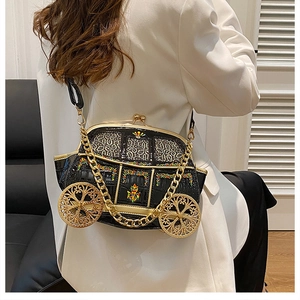 Carriage-shaped crossbody bag with gold wheels and chain strap on a white blazer