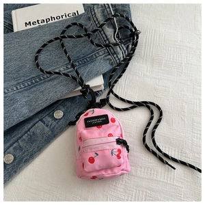 Detail view of pink mini bag with cherry pattern and adjustable black and white cord