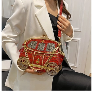 Detail of red carriage shaped handbag with gold hollow pattern and chunky chain strap