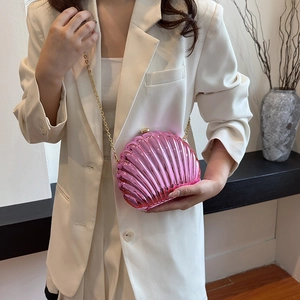 Borsa a tracolla rosa a forma di conchiglia con catena dorata su blazer bianco