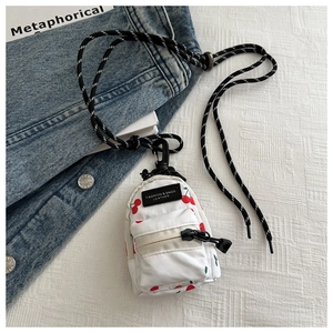 Detailed shot of mini canvas pouch with cherry print on white fabric and denim