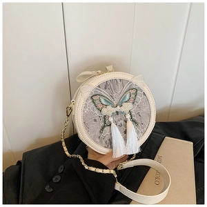 Détail du sac bandoulière rond blanc avec broderie papillon, perles et glands en soie