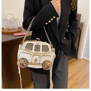 Detailed view of white carriage-shaped chain bag with crocodile texture and gold wheels