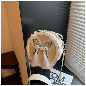 Détail du sac à bandoulière rond blanc avec broderie papillon 3D et pompons en perles