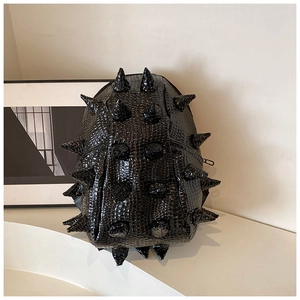 Detail shot of black punk backpack with shiny crocodile texture and 3D conical studs