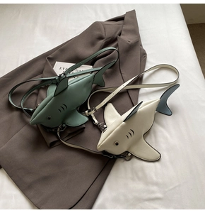 Close-up of shark-shaped crossbody bags in mint green and off-white PU leather