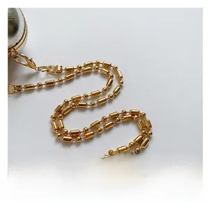 Detail of the high-polished gold metal ball chain strap with lobster clasp on a silver bag