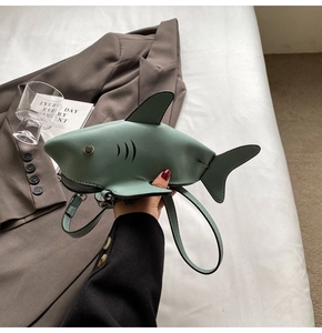 Detail of the shark-shaped crossbody bag in sage green featuring stitching and fins