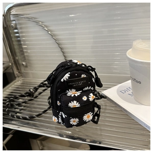 Detailed macro view of a mini black daisy print crossbody bag with silver zipper and leather tag